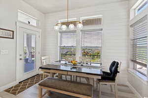 Dining area with wood finished floors, plenty of natural light, baseboards, and wood walls