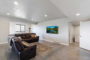 Living room featuring concrete flooring, baseboards, recessed lighting, and a textured ceiling