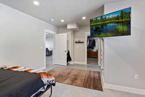 Bedroom featuring concrete flooring, recessed lighting, baseboards, a walk in closet, and a closet