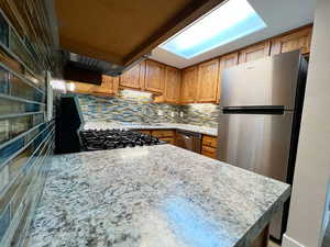 Kitchen featuring stainless steel appliances, brown cabinets, a sink, and decorative backsplash