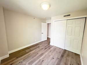 Unfurnished bedroom featuring wood finished floors, baseboards, and a closet