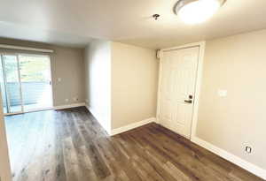 Unfurnished room featuring dark wood-style floors, baseboards, and a pendent fire sprinkler