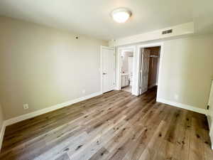 Unfurnished bedroom with wood finished floors, baseboards, a walk in closet, and a closet