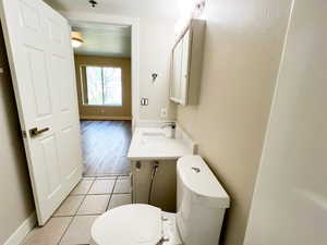 Half bathroom featuring toilet, vanity, tile patterned floors, and baseboards