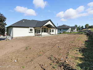 Back of house featuring a patio, a shingled roof, and stucco siding