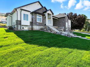 View of front facade with stone siding, board and batten siding, and a front yard