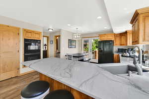 Kitchen with black appliances, a sink, a peninsula, light wood finished floors, and recessed lighting