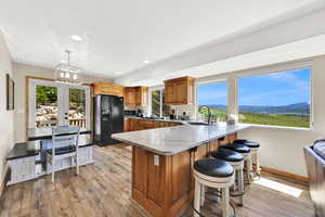 Kitchen featuring black fridge with ice dispenser, a sink, stainless steel microwave, a peninsula, and light wood finished floors