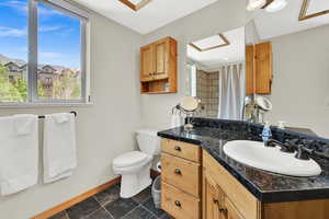 Full bathroom with baseboards, vanity, toilet, and plenty of natural light