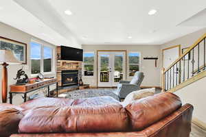 Living room with french doors, wood finished floors, baseboards, recessed lighting, and stairway