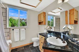 Full bath with baseboards, vanity, toilet, and shower / bathtub combination with curtain