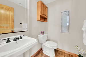 Bathroom with a sink, baseboards, wood finished floors, and toilet