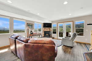 Living area with a fireplace, baseboards, light wood-style floors, recessed lighting, and french doors