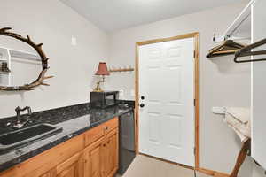 Kitchen with a sink, fridge, and dark stone countertops