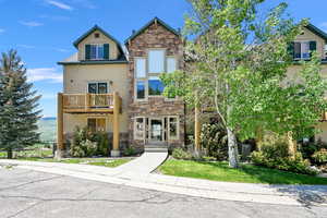View of front of home with stone siding and a balcony