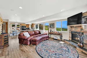 Living area with plenty of natural light, light wood-type flooring, a fireplace, and recessed lighting