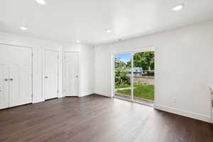 Unfurnished bedroom with access to outside, recessed lighting, dark wood finished floors, and two closets
