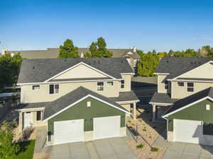 Traditional-style house featuring a residential view, stucco siding, a garage, concrete driveway, and roof with shingles
