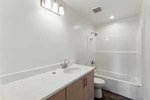 Bathroom with toilet, vanity, and  shower combination