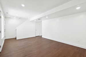 Basement featuring dark wood-type flooring, stairs, and recessed lighting