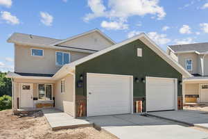 View of front of house featuring an attached garage, concrete driveway, and stucco siding