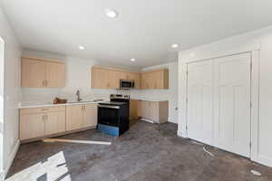 Kitchen with appliances with stainless steel finishes, light brown cabinetry, concrete flooring, a sink, and recessed lighting
