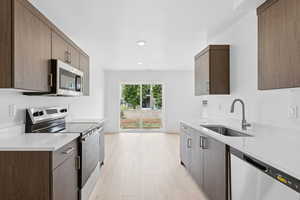 Kitchen featuring appliances with stainless steel finishes, light countertops, light wood-style floors, modern cabinets, and recessed lighting
