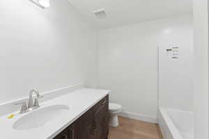 Full bathroom with wood finished floors, toilet, a tub, vanity, and baseboards