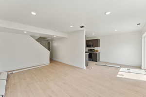 Unfurnished living room featuring recessed lighting, light wood-style floors, and baseboards