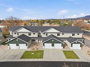 Traditional-style house with stucco siding, concrete driveway, a residential view, a shingled roof, and a garage