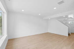 Basement with light wood-style flooring, stairway, and recessed lighting