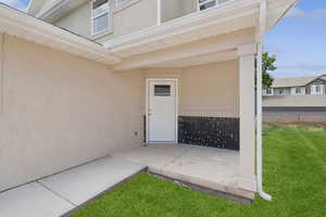Entrance to property with a lawn, stucco siding, and a patio