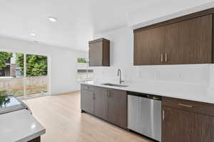 Kitchen with dishwasher, dark brown cabinets, light countertops, light wood-style floors, and recessed lighting