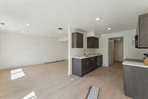 Kitchen featuring a sink, dark brown cabinets, light wood-type flooring, light countertops, and recessed lighting