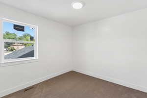 Empty room with dark colored carpet and baseboards