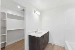 Bathroom featuring wood finished floors, vanity, baseboards, and a bathtub