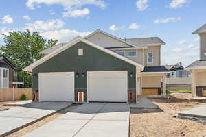 View of front of property featuring concrete driveway, stucco siding, and roof with shingles