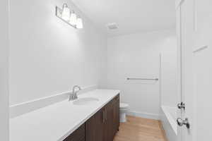 Bathroom featuring vanity, wood finished floors, a tub to relax in, and a shower