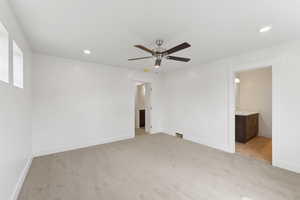Unfurnished bedroom with light colored carpet, baseboards, recessed lighting, ensuite bath, and a ceiling fan