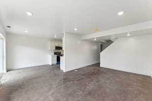 Unfurnished living room featuring concrete floors, recessed lighting, and baseboards