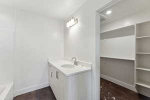 Full bath featuring vanity, wood finished floors, a tub, and baseboards