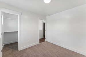 Unfurnished bedroom with carpet floors, baseboards, a closet, and a spacious closet
