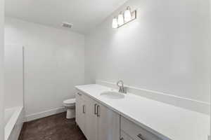 Full bathroom with vanity, toilet, concrete flooring, and baseboards