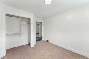 Unfurnished bedroom featuring carpet floors, baseboards, and a closet