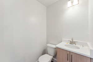 Half bath featuring toilet, vanity, and baseboards