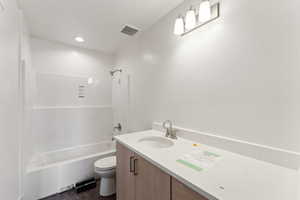 Bathroom with toilet, vanity, and  shower combination