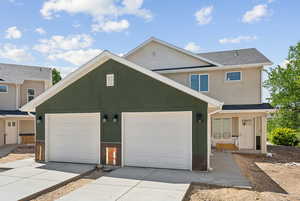 View of front facade featuring driveway, stucco siding, a garage, and roof with shingles
