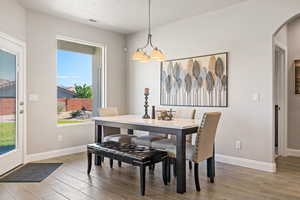 Dining area featuring wood finished floors, arched walkways, a chandelier, and baseboards