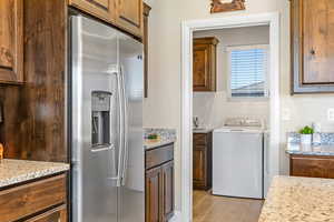 Laundry area with cabinet space, light wood-style floors, and independent washer and dryer