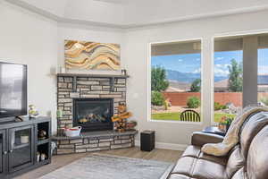 Living room featuring wood finished floors, a mountain view, a stone fireplace, and baseboards